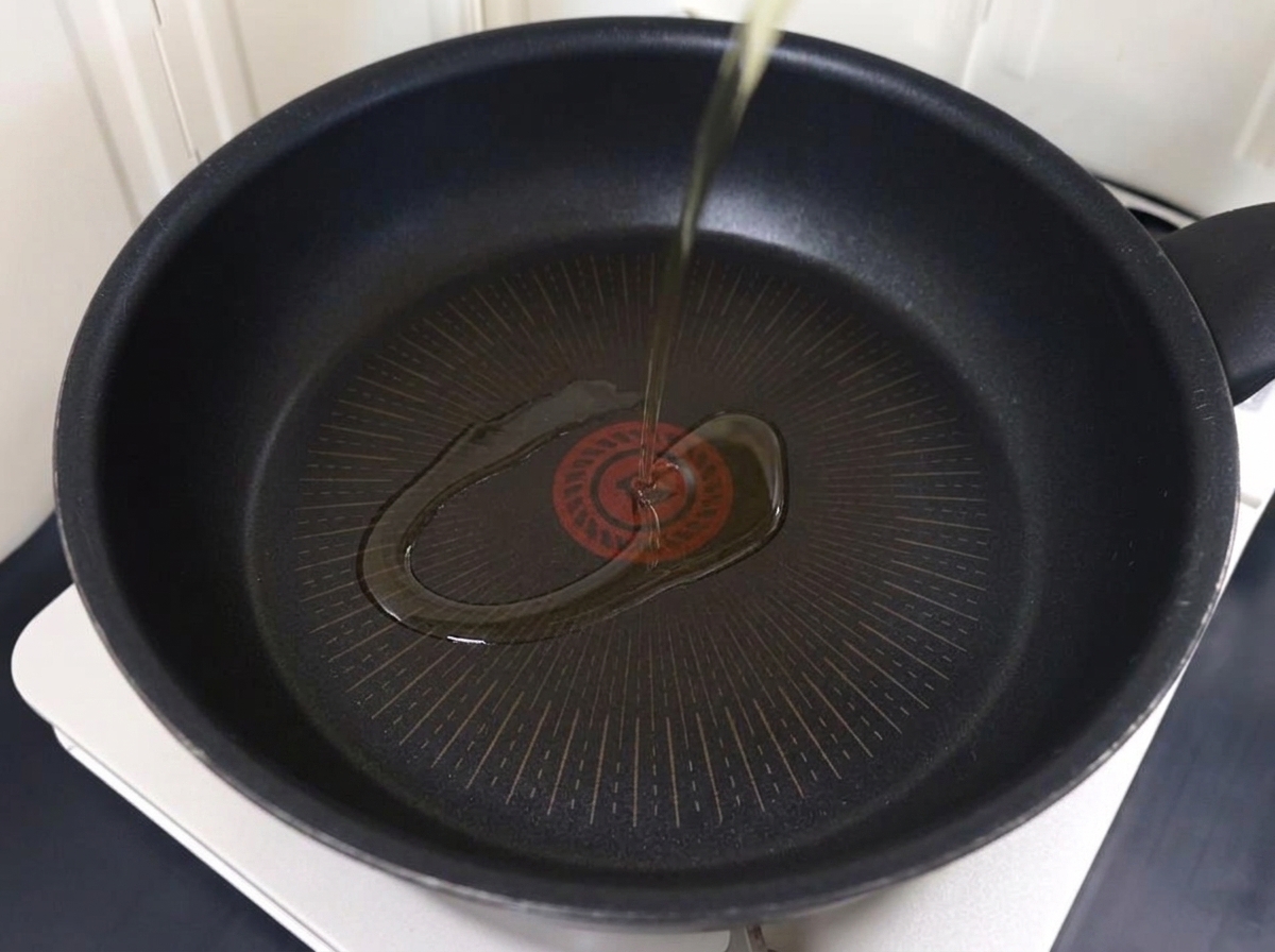 Dünn geschnittenes Schweinefleisch brät in einer Pfanne mit heißem Öl.
