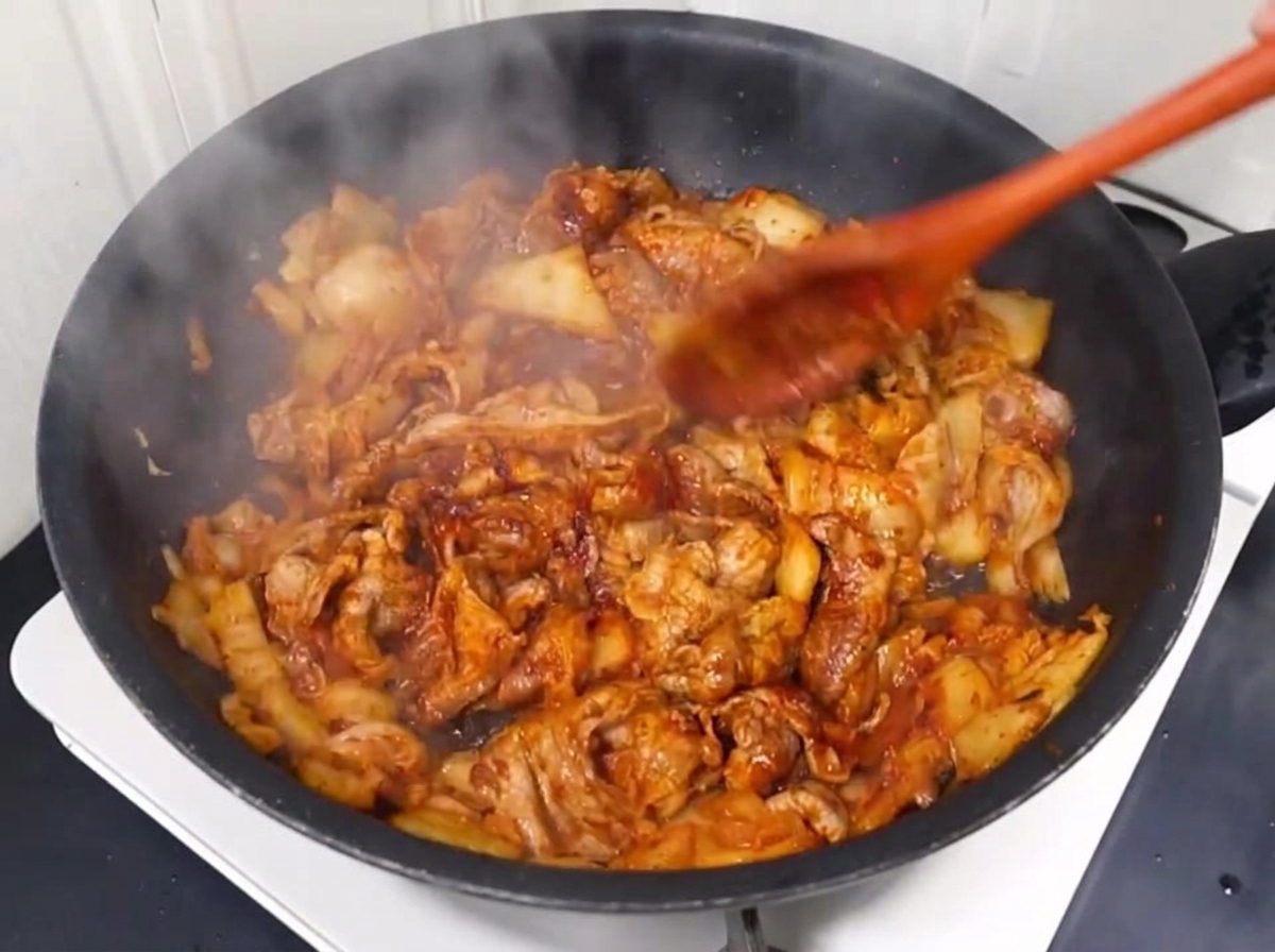 Wasser wird in die Pfanne zur Fleisch-Kimchi-Mischung gegossen.