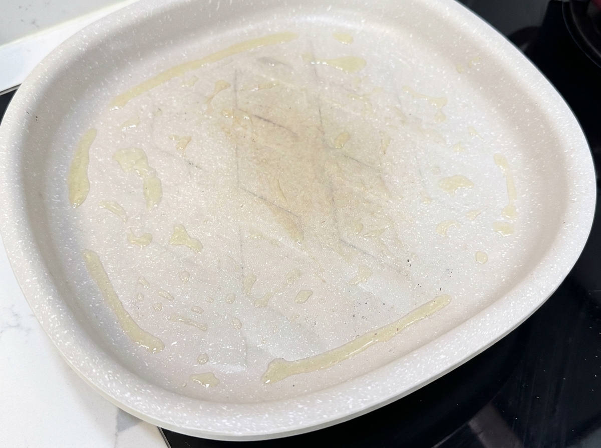 Speckscheiben liegen flach in einer heißen Antihaft-Pfanne und beginnen zu braten.