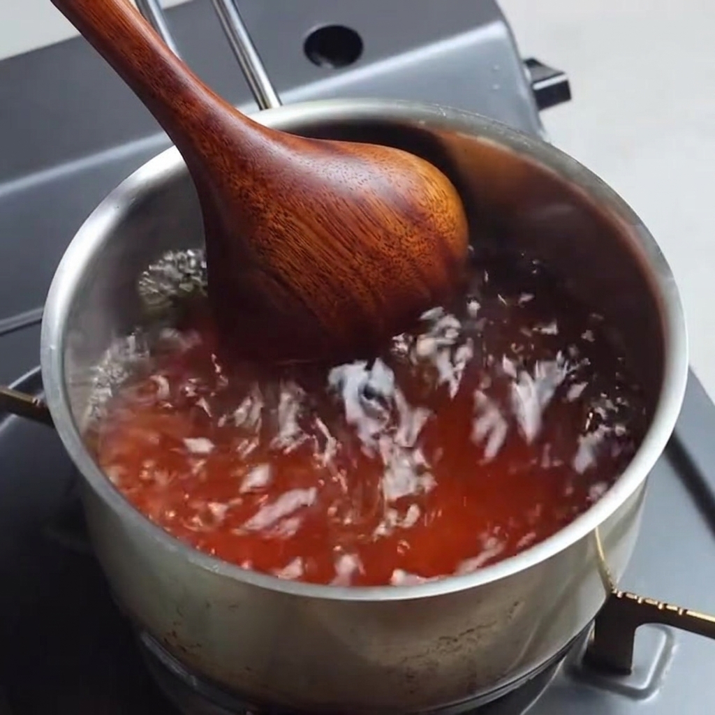 Die gewürzte Ramen-Brühe köchelt in einem Topf und wird umgerührt.