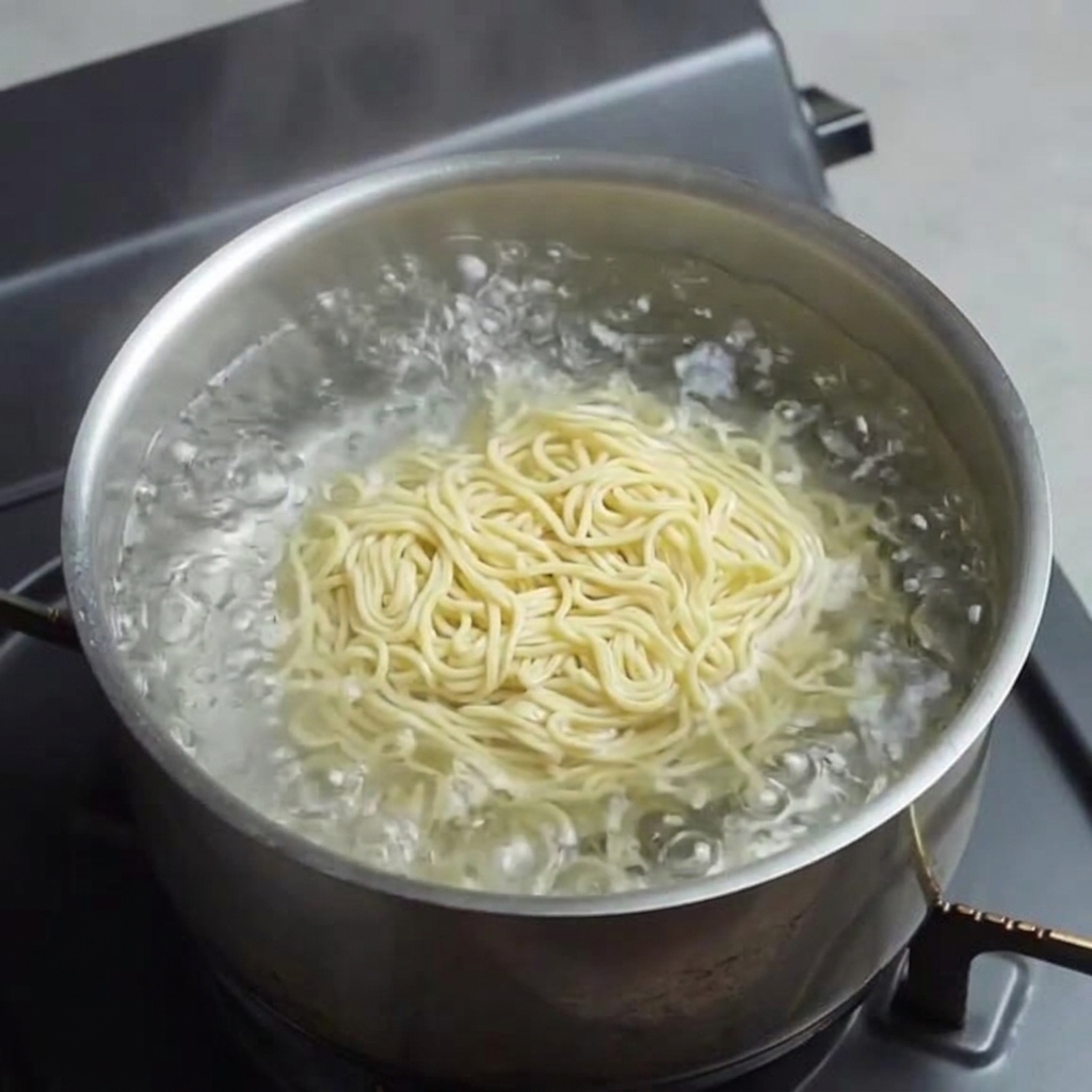 Frische gelbe Ramen-Nudeln garen in kochendem Wasser.