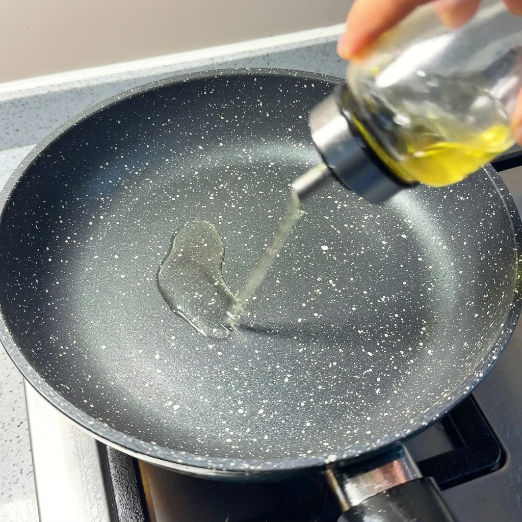 Nahaufnahme von Speiseöl, das in eine vorgewärmte, gesprenkelte Antihaftpfanne gegossen wird.