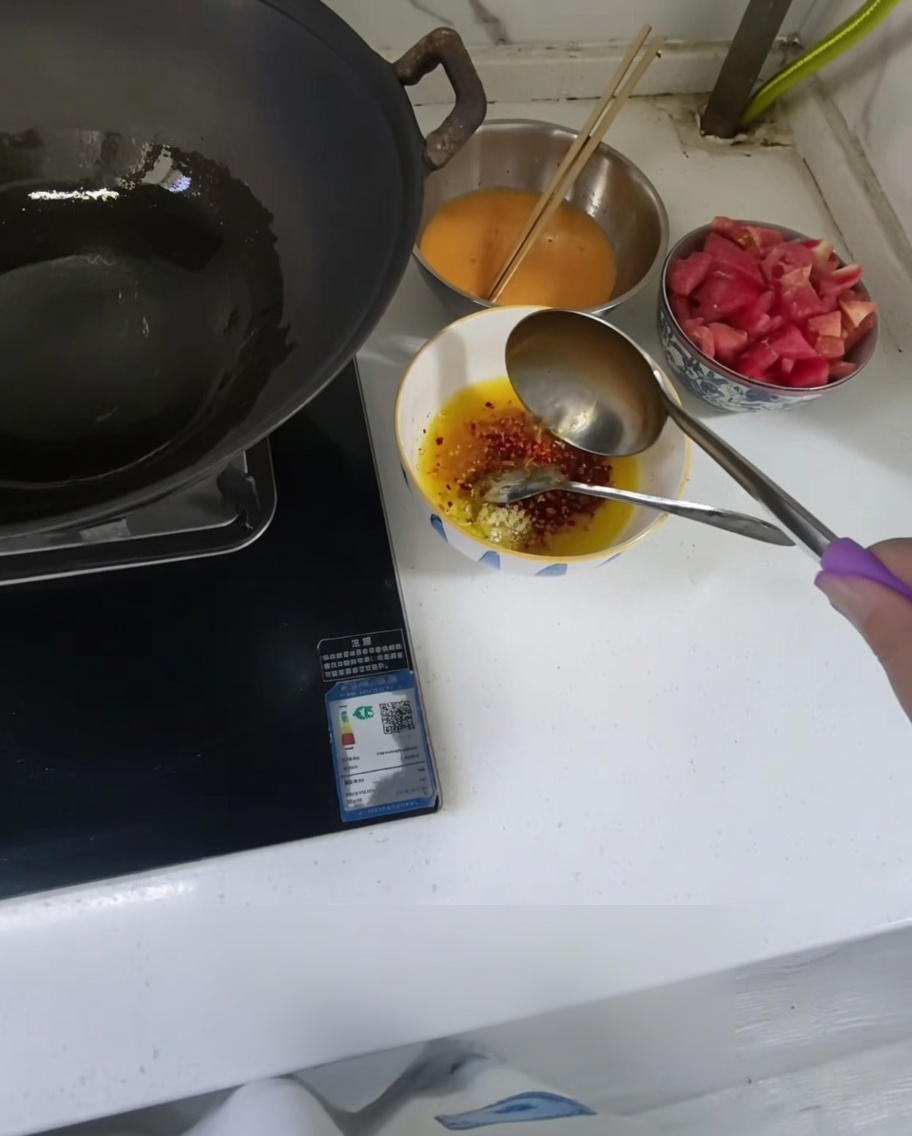 Heißes Öl wird aus einer Kelle in eine kleine Schüssel mit Knoblauch und Chilipulver gegossen.