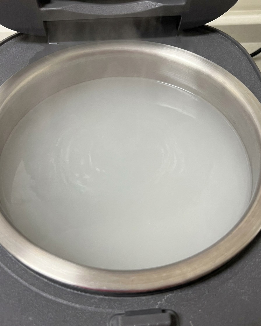 Rohe Schweinerippchen in einem mit kochendem Wasser gefüllten Reiskocher.