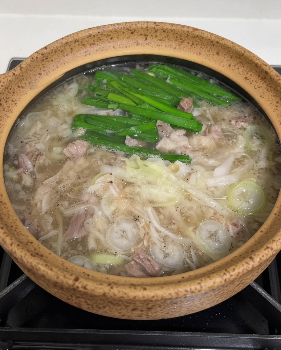 Ein Löffel rote Chilipaste wird in die dampfende Suppe eingerührt.
