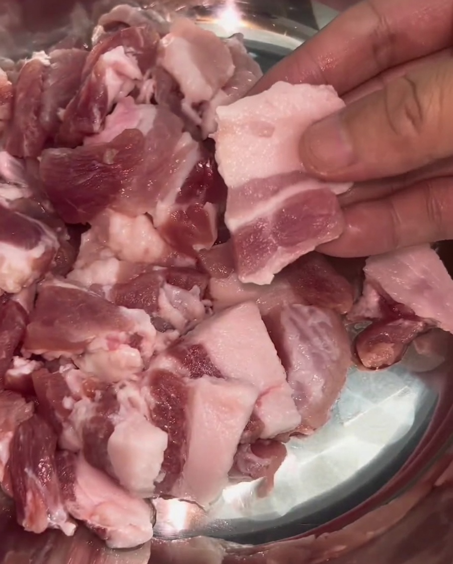 Gleichmäßig dünne Scheiben vom Schweinebauch mit sichtbaren Fett- und Fleischschichten in einer Edelstahlschüssel.