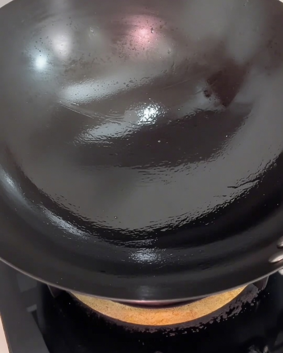 Schweinebauchscheiben im Wok, die eine leichte, goldbraune Kruste auf der Oberfläche zeigen.