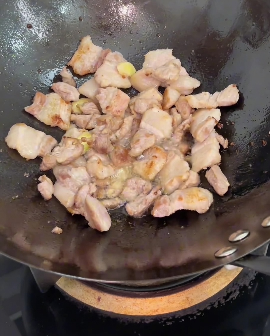Sojasauce wird über den gebratenen Schweinebauch und Ingwer im Wok gegossen.