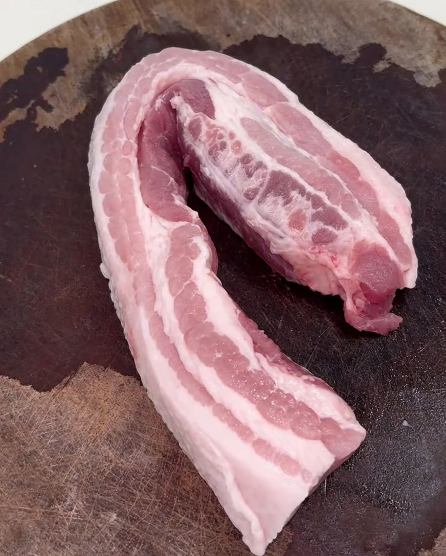 Schweinebauchscheiben bräunen in einem heißen Wok.