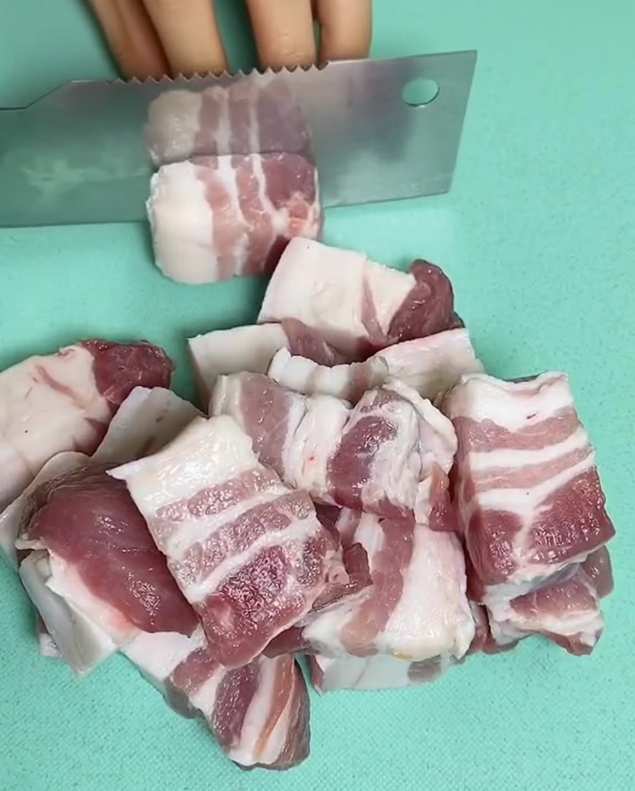 Rohe Schweinebauchstücke in einem Topf mit kaltem Wasser, Ingwer und Kochwein.