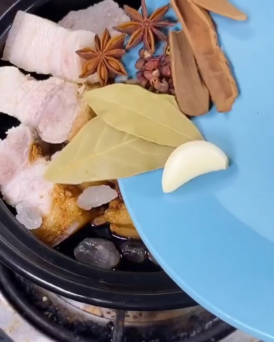 Sternanis, Lorbeerblätter, getrocknete Mandarinenschale und Frühlingszwiebeln werden in den Topf gegeben.