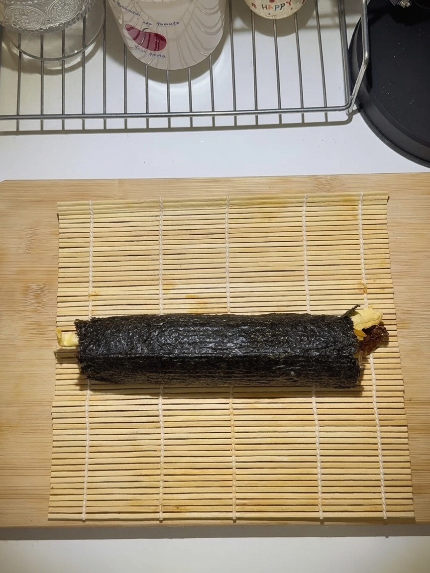 Fest gerolltes Gimbap auf einer Bambusmatte.