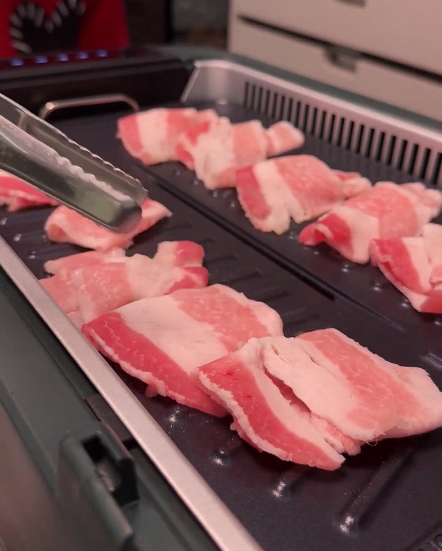 Schweinebauchscheiben bräunen auf der Grillfläche.