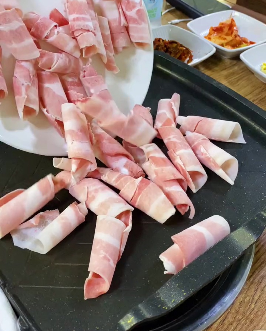 Dünne Scheiben rohen Schweinebauchs auf einem heißen Grill.