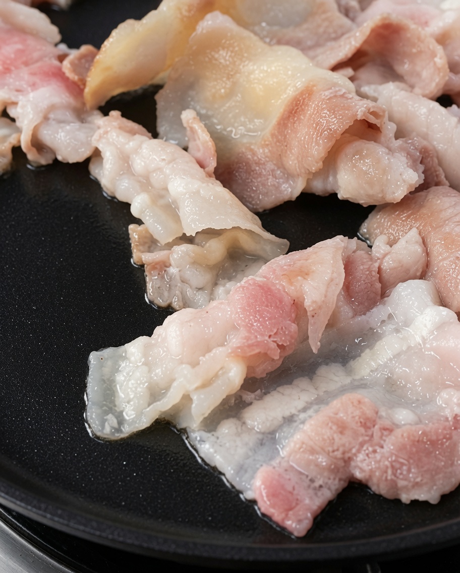 Goldbraun gegrillte Schweinebauchscheiben auf einem heißen Grill.