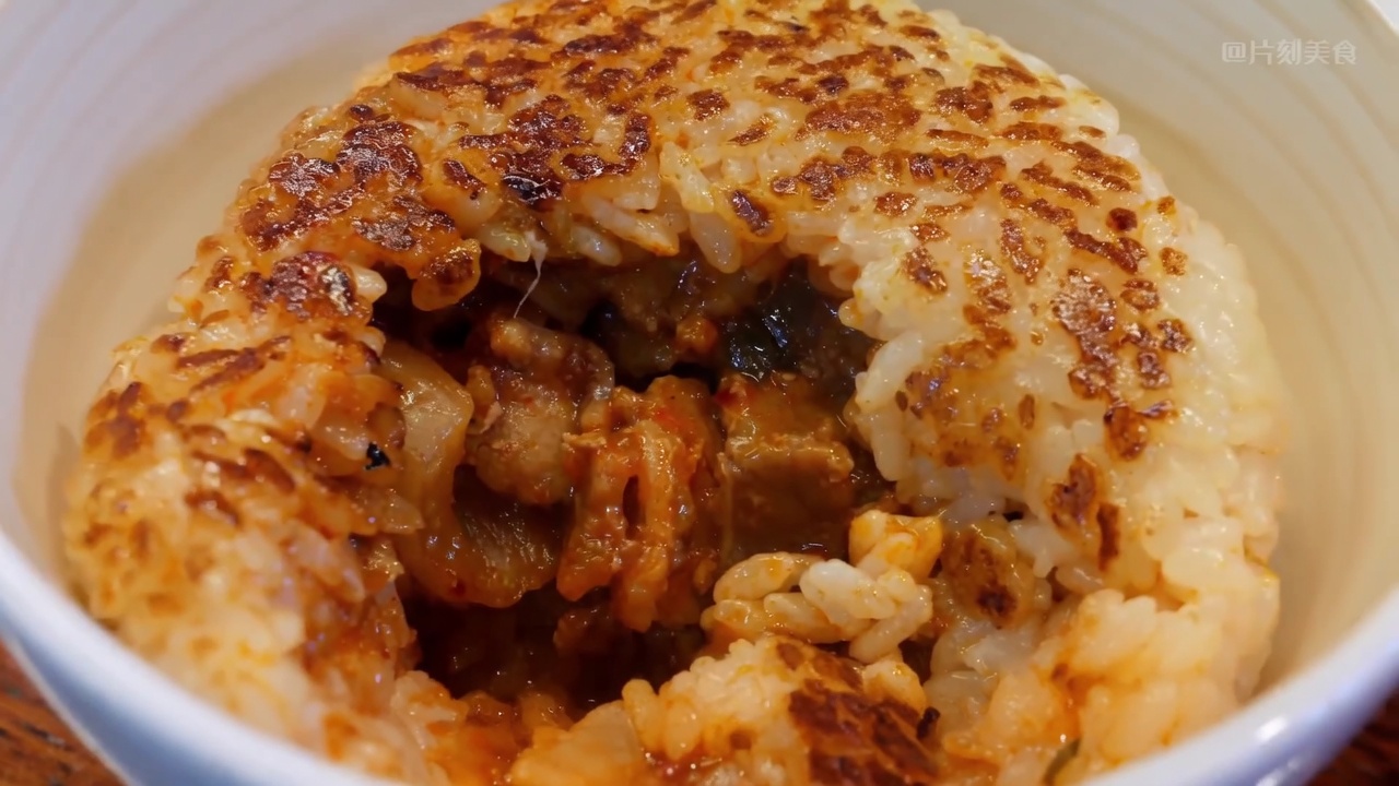 Ein aufgeschnittenes gegrilltes Reisbällchen, das die würzige Kimchi-Schweinebauch-Füllung in einer knusprigen Reishülle zeigt.