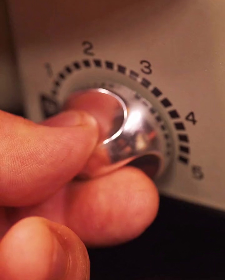 Hand, die den Hitzeregler eines Elektrogrills einstellt.
