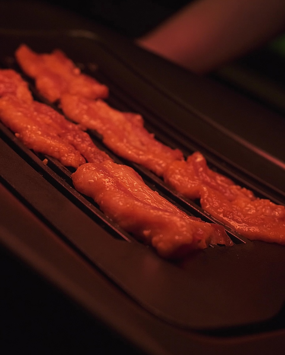 Marinierte Schweinebauchscheiben, die auf einem heißen Elektrogrill brutzeln.