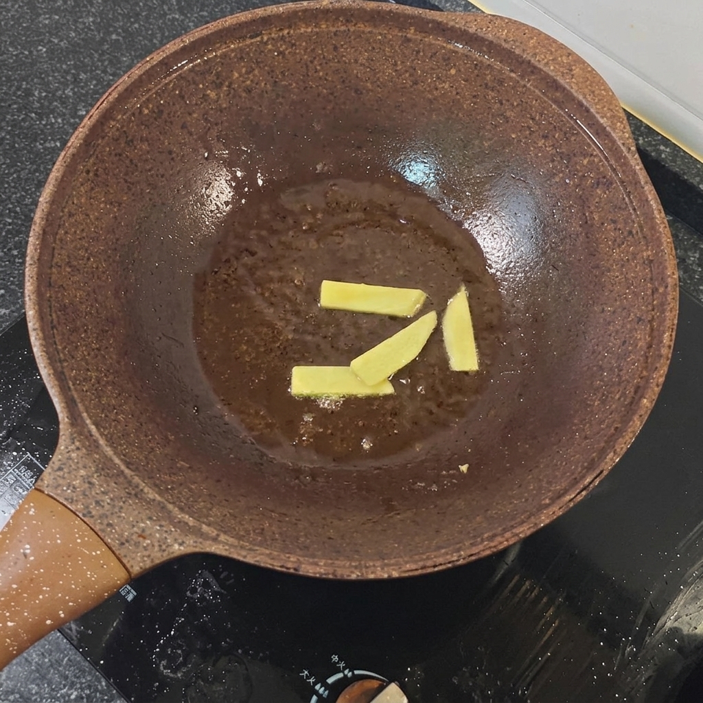 Ingwerscheiben und rote Zwiebelstücke werden in einer Pfanne angedünstet.