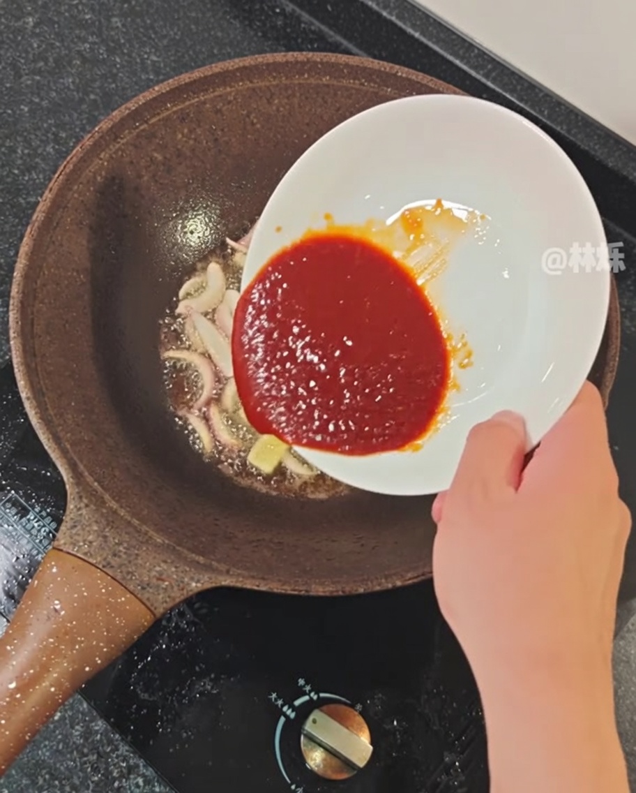 Würzige Sauce wird in eine Pfanne mit den angedünsteten Aromaten gegossen.