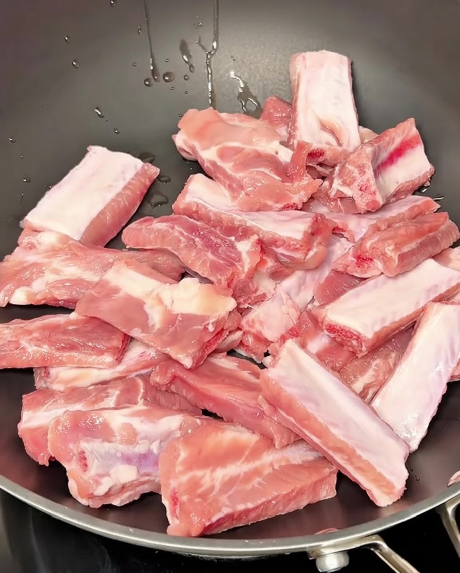 Schweinerippchen köcheln in einem Topf mit Wasser und Gewürzen während des Blanchierens.