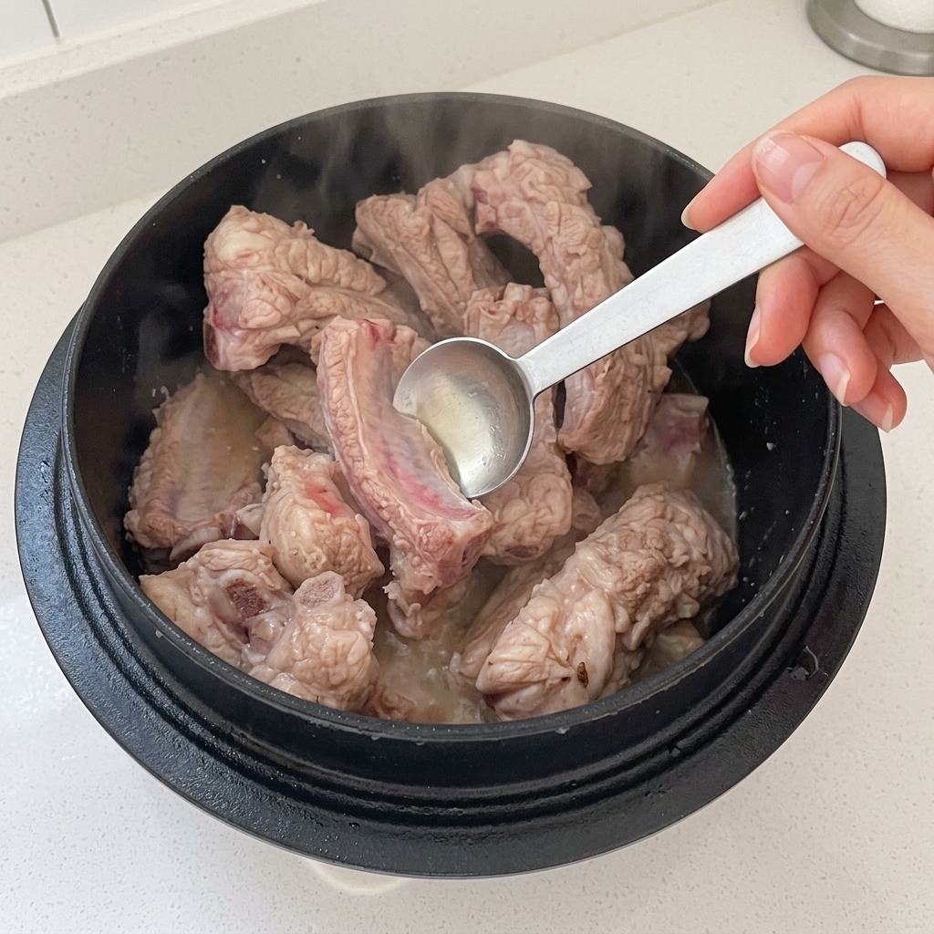 Essig wird in einen Topf mit anbratenden Schweinerippchen gegossen.