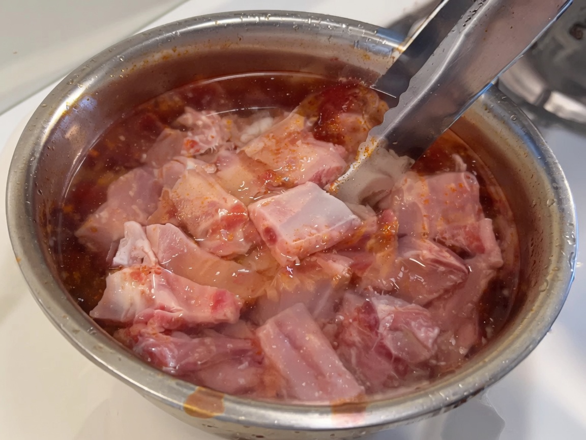Frische rohe Schweinerippchen in einer Schüssel mit klarem Wasser eingetaucht.