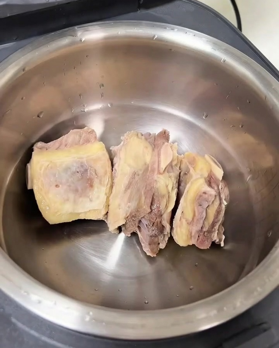 Der Innentopf eines Reiskochers mit gesäuberten Rinderrippchen und verschiedenen Aromaten.