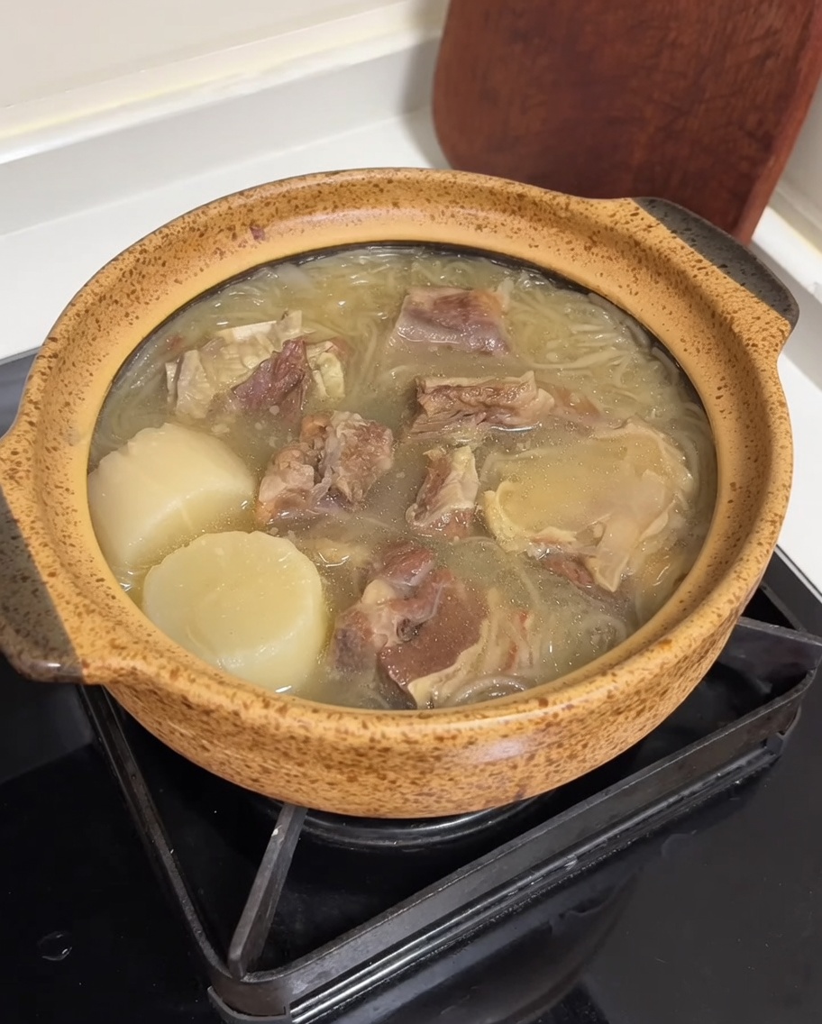 Ein Keramiktopf voller Suppe, garniert mit gelben Eierstreifen und grünen Zwiebeln.