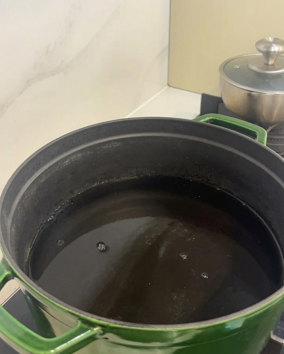 Rohe Rinderrippenstücke in einem großen grünen Topf mit kaltem Wasser.