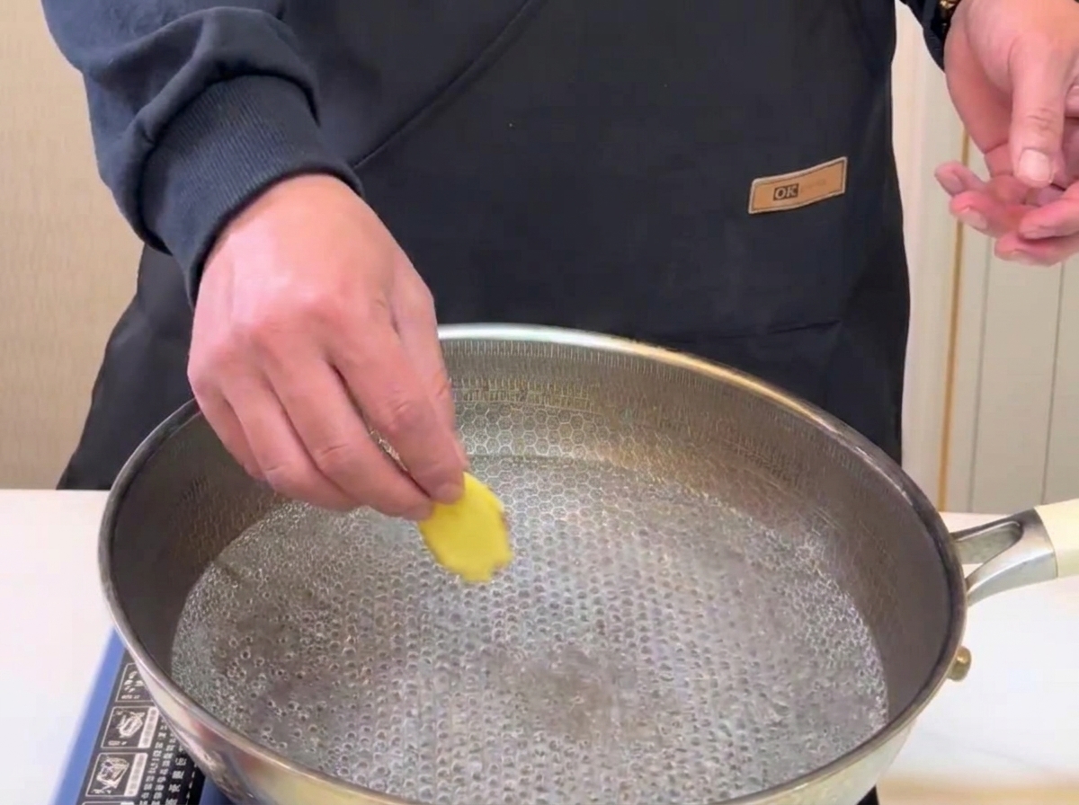 Ingwerscheiben werden zum Blanchieren in einen Topf mit kochendem Wasser gegeben.
