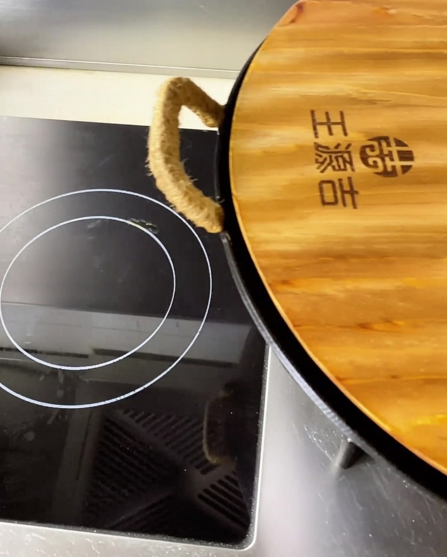 Nahaufnahme von zarten, geschmorten Schweinerückenstücken in einer scharfen, aromatischen roten Brühe in einem großen Wok.