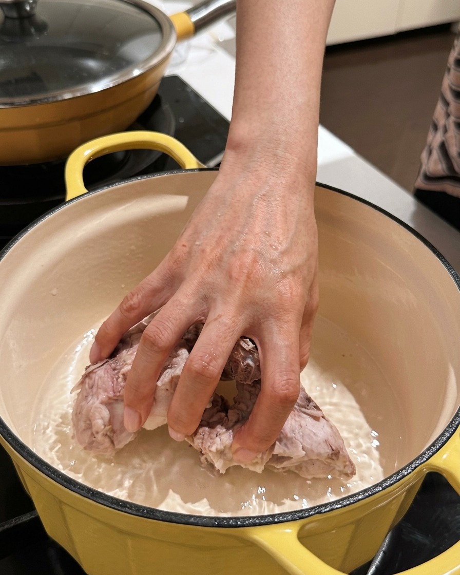 Hand legt saubere Rippchenstücke in einen leeren Topf.