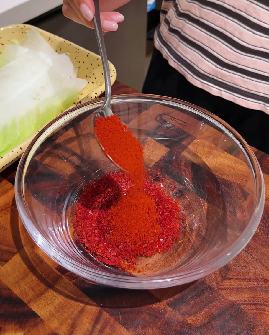 Rotes Chilipulver wird in eine Glasschale zu anderen Gewürzen gegeben.