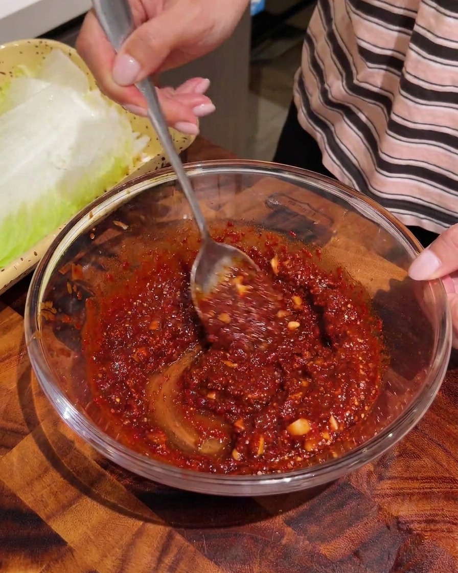 Gezupfte Kohlstreifen werden mit roter Würzpaste in einer Schale vermengt.