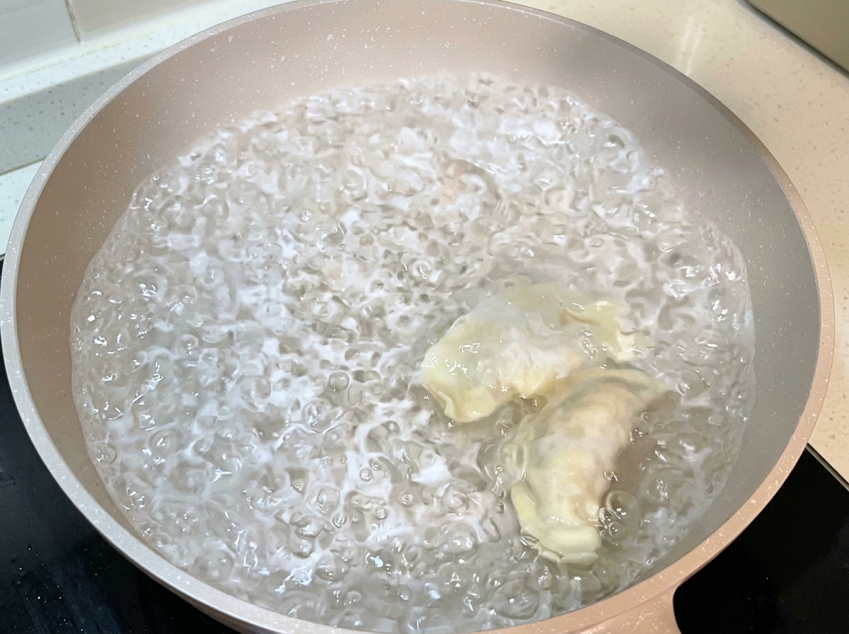Gefaltete Dumplings werden in einen großen Topf mit kochendem Wasser gegeben.