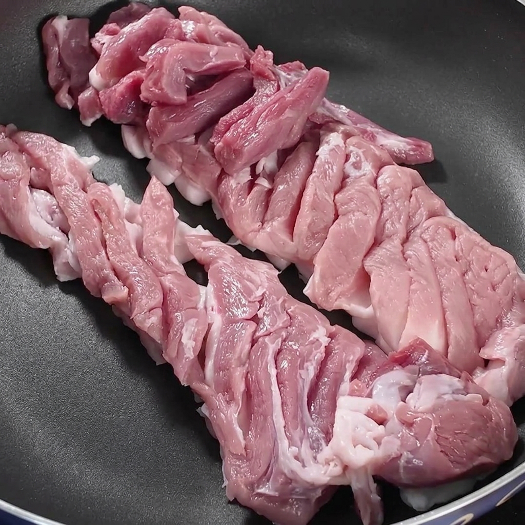 Schweinebauchscheiben in einer trockenen Pfanne auf dem Herd.