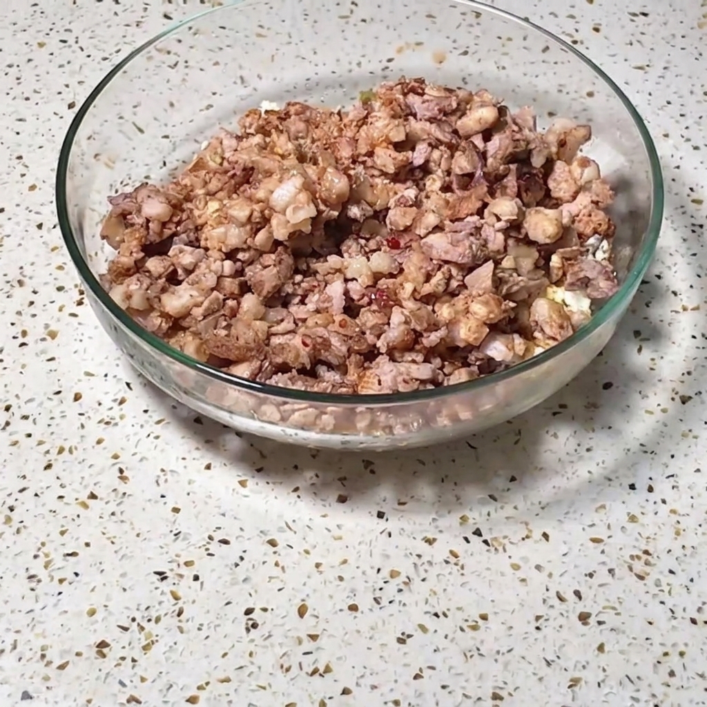 Gehacktes Fleisch, Eier und gewürztes Gemüse in einer Glasschüssel.