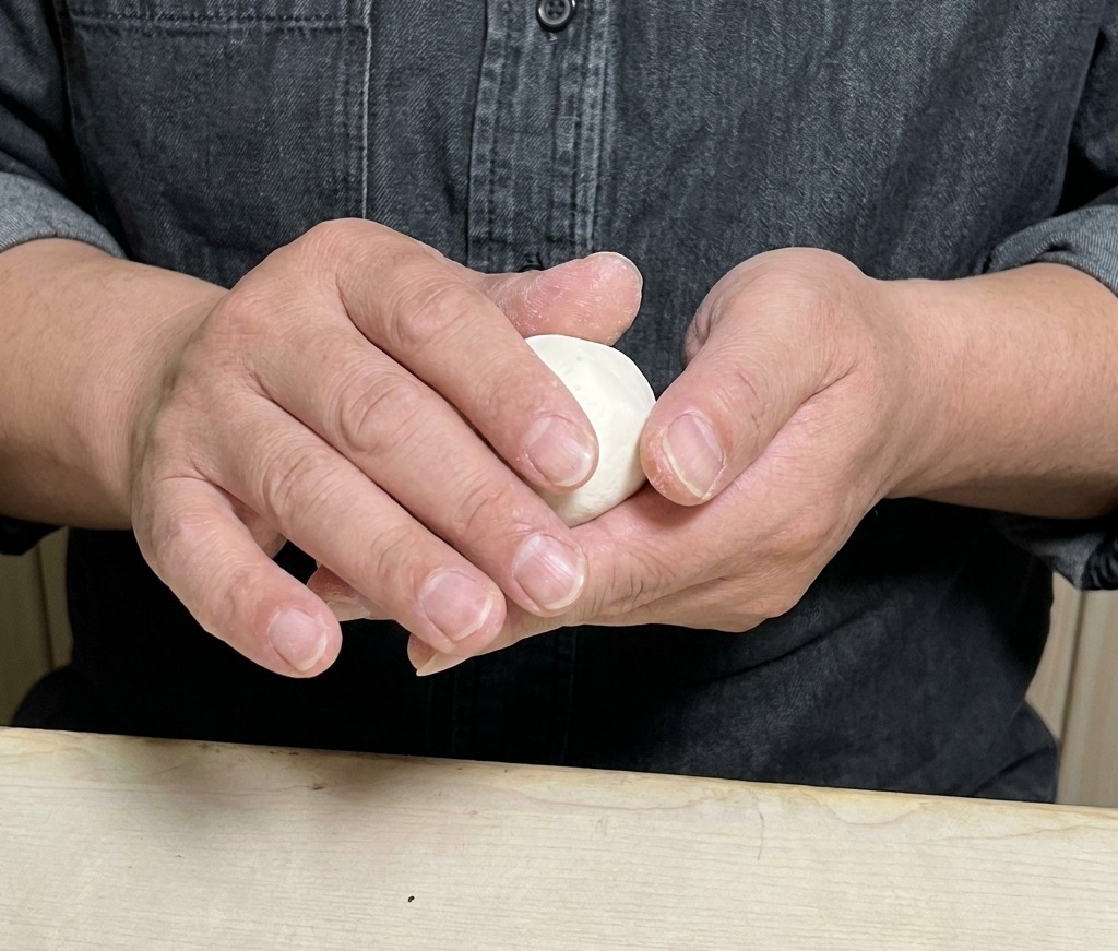 Hände beim Zusammenlegen und Verschließen eines Dumplings.