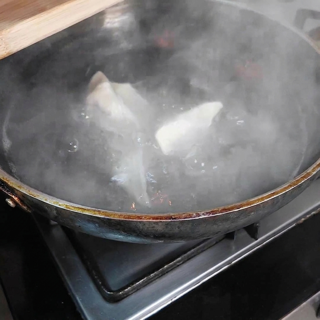 Dumplings in einem Topf mit kochendem Wasser.