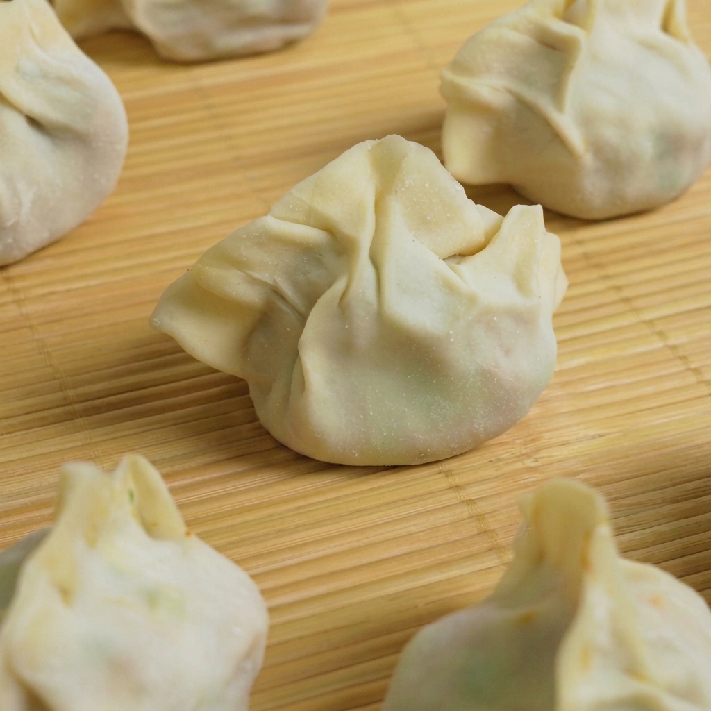 Mehrere vorbereitete Dumplings werden zum Kochen in einen Topf mit kochendem Wasser gegeben.