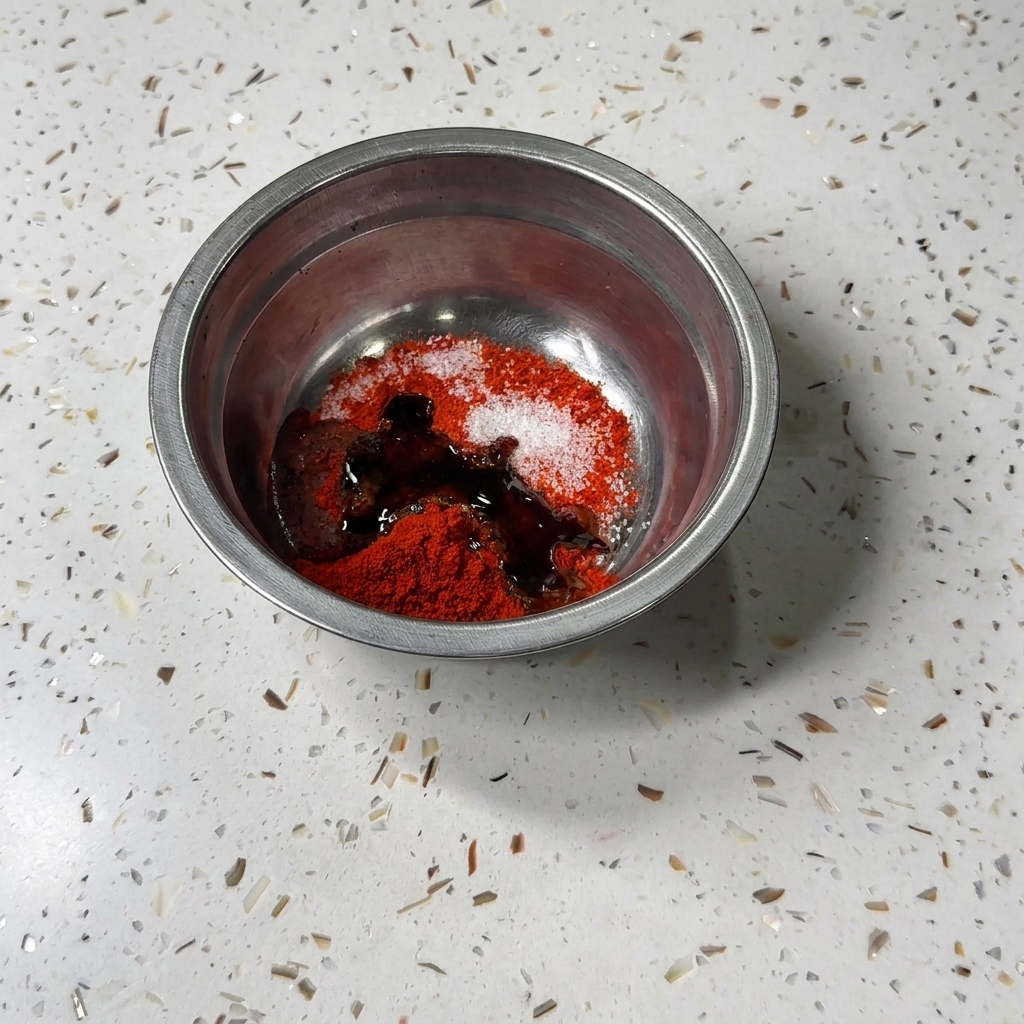 Dunkle fluessige Sojasauce und Austernsauce werden in die Metalschuessel mit Chilipulver und Zucker gegossen.