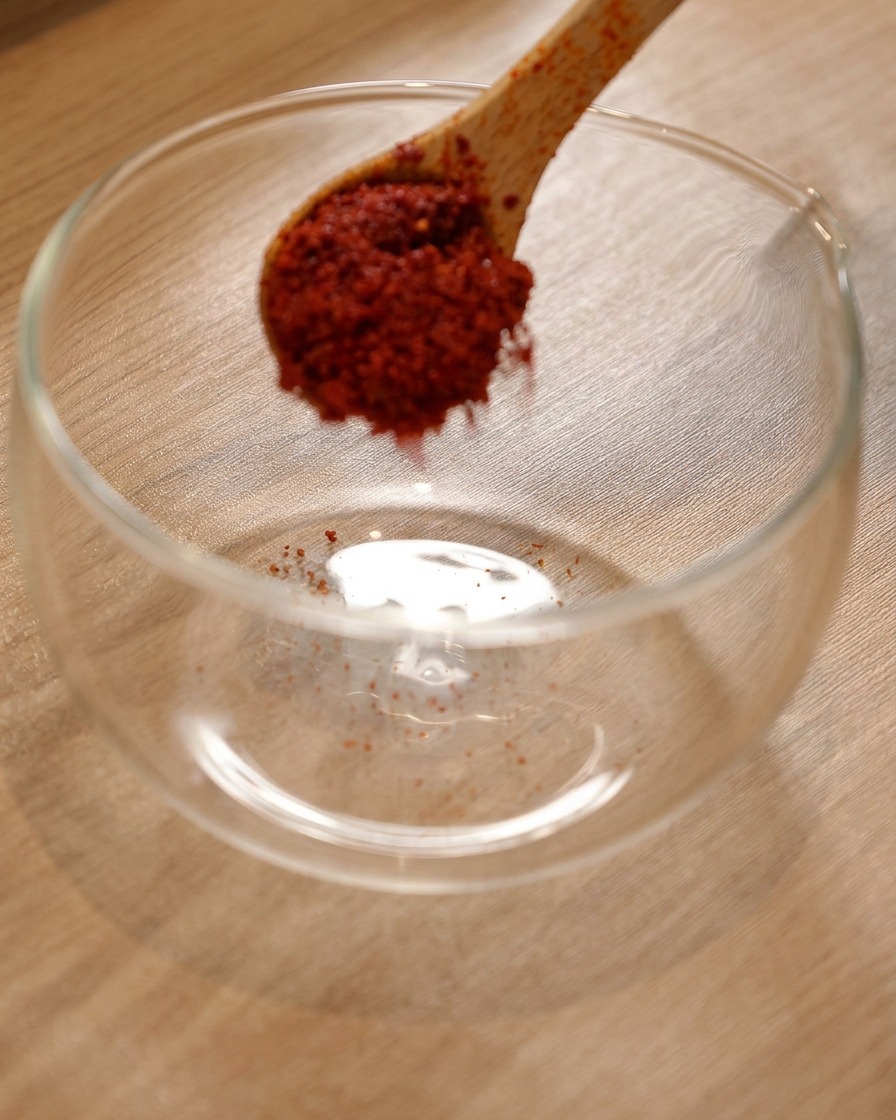 Chilipulver in einer Glasschüssel mit hinzugefügter koreanischer scharfer Sauce und heller Sojasauce.