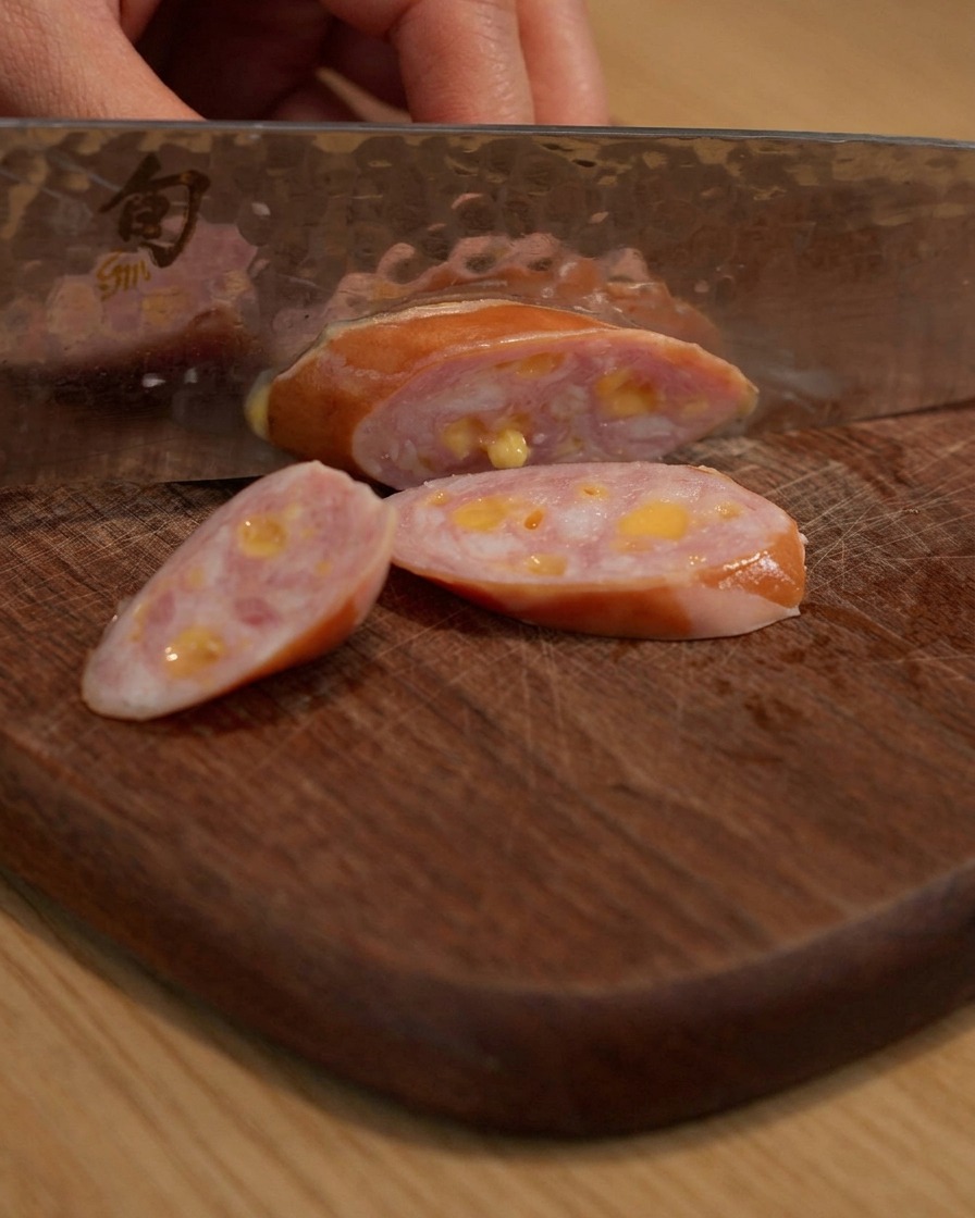 Wurst wird auf einem Holzschneidebrett geschnitten.