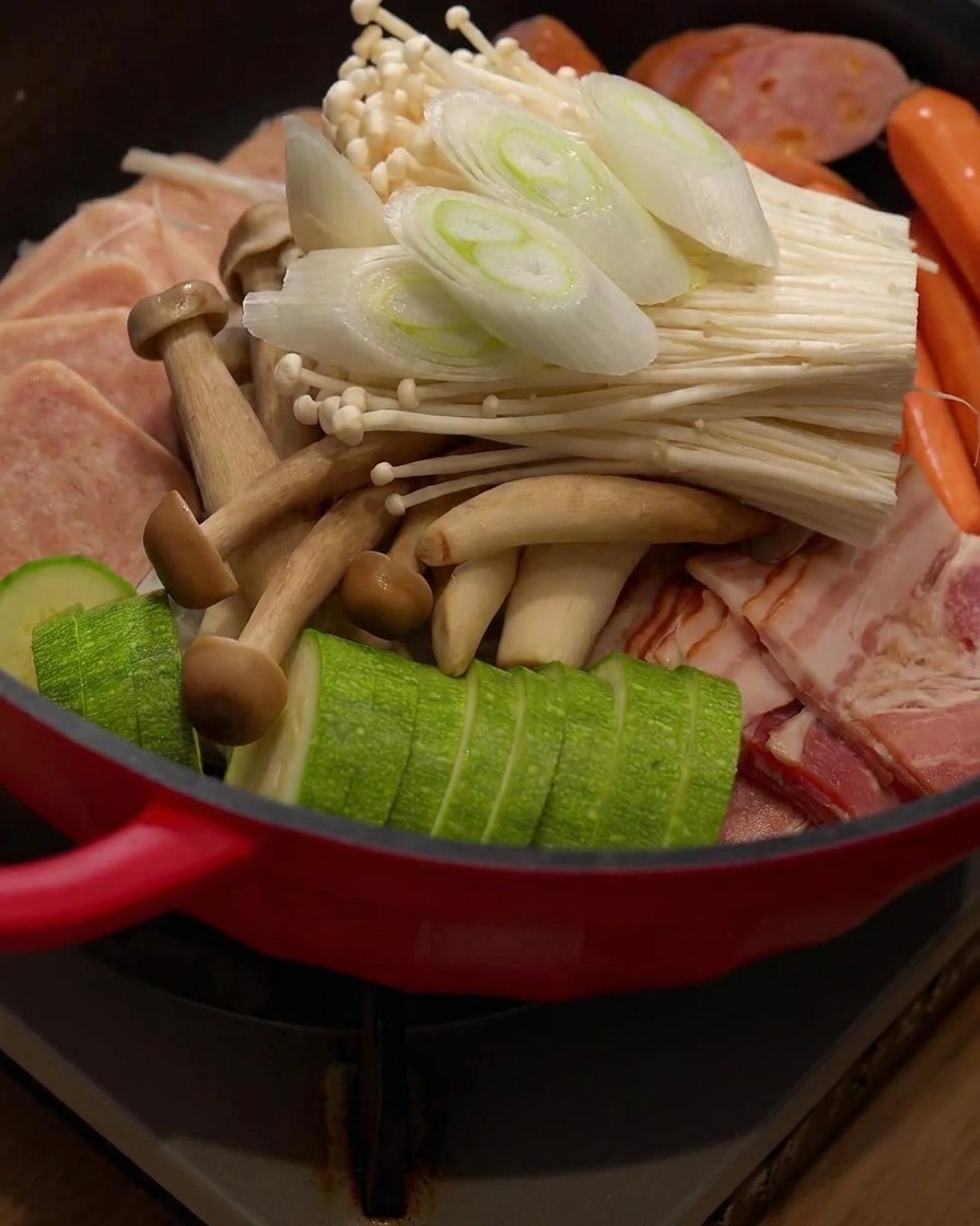 Frisch geschnittene Frühlingszwiebelstücke werden auf die Zutaten im Hot Pot gegeben.