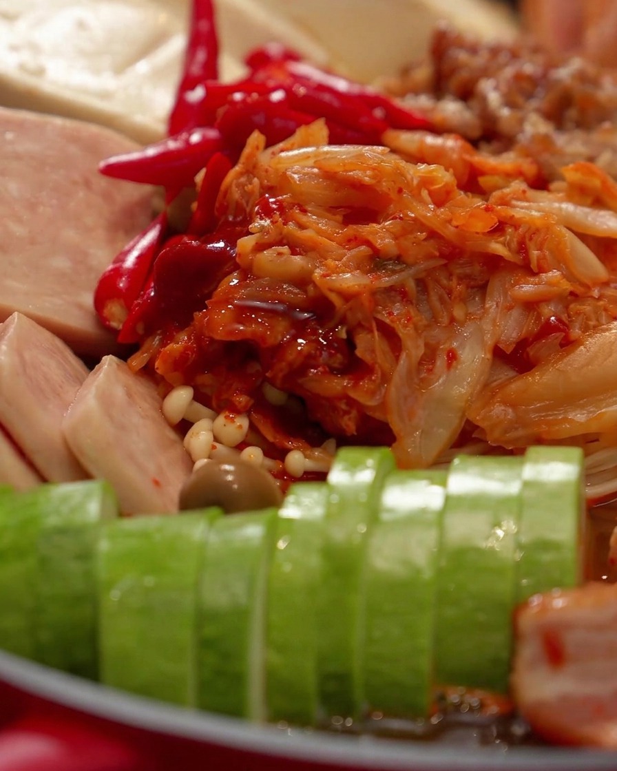 Eine Nahaufnahme eines Glasdeckels, der die Zutaten im roten Hot Pot abdeckt.