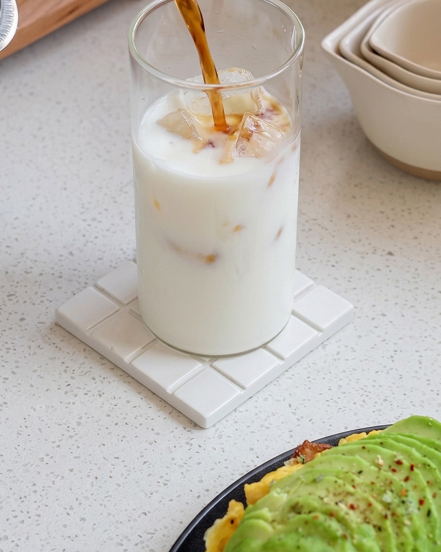 Frischer Espresso wird in ein Glas mit Eismilch gegossen, wodurch ein fließender Farbverlauf entsteht.