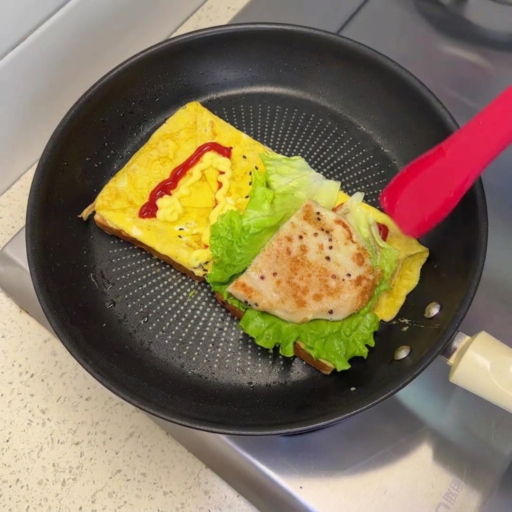 Ein goldbraun gebratenes Hähnchenpatty liegt auf dem frischen Salat in der Pfanne.
