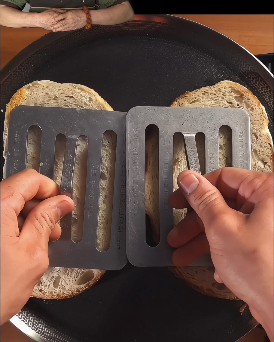 Brot-Scheiben werden in einer schwarzen Pfanne angedrückt und bis zur Bräunung getoastet.