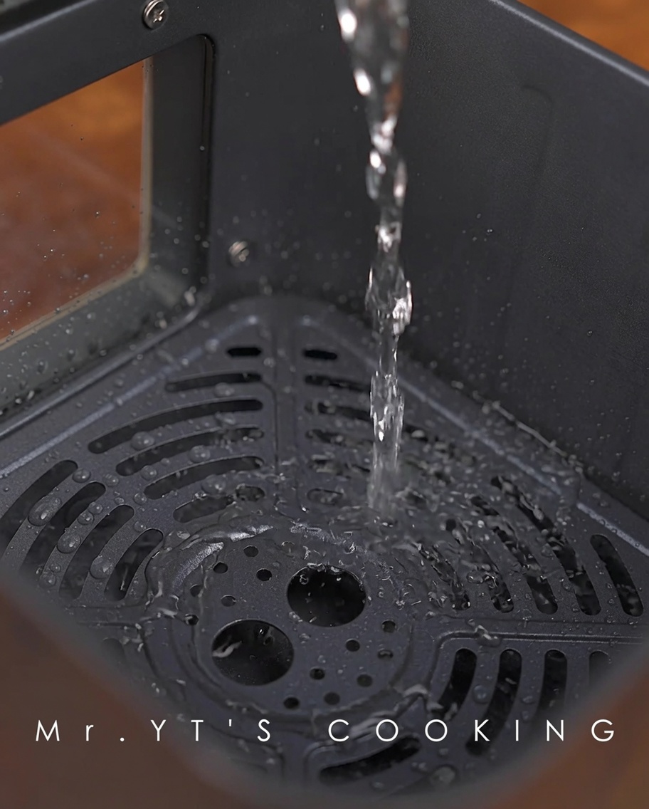 Wasser wird in den Boden des Heißluftfritteusenkorbs gegossen.